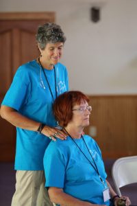 Professional masseuse volunteer giving a neck and shoulder massage at camp